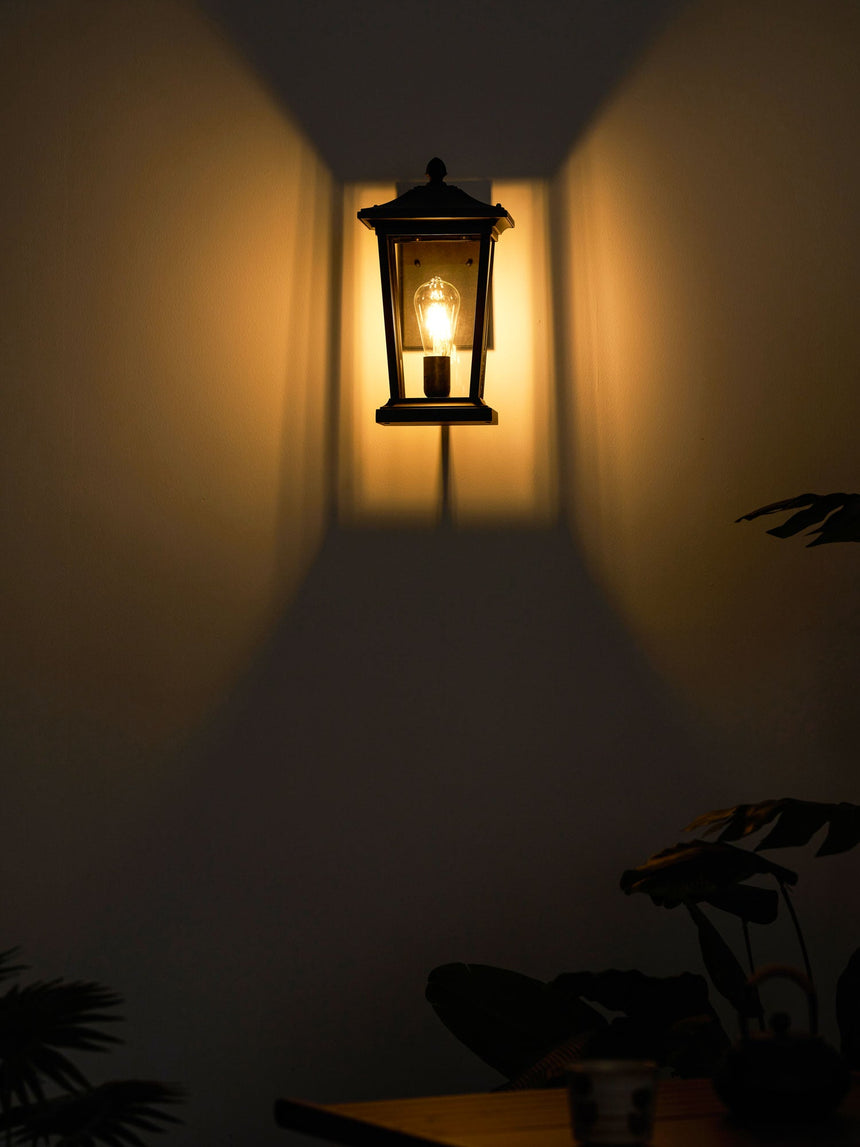 The lantern lit at night above a small table and tropical plants