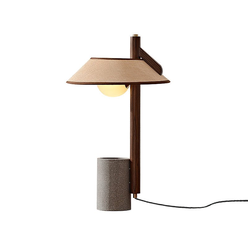 The cement base lamp lit, the glass bulb visible under the flat shade