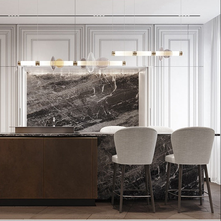 The linear bar lit above a dark kitchen island with bar stools