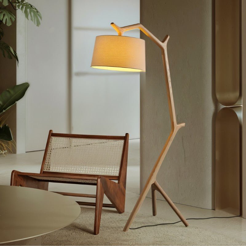 The lit lamp leaning over a cane and timber lounge chair on a pale stone floor