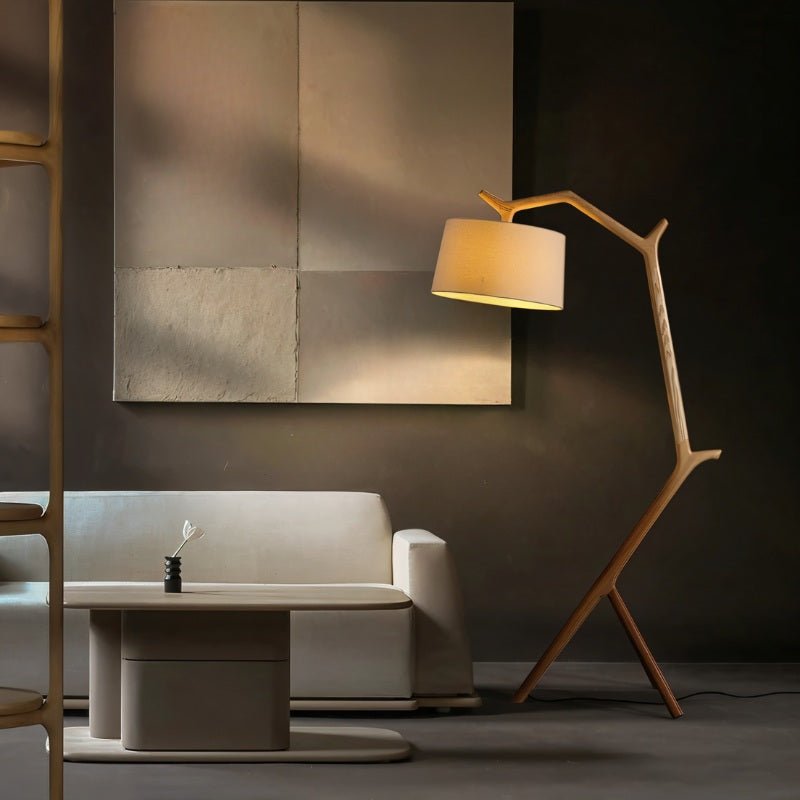 The lit lamp beside a sofa against a dark wall with a large framed artwork
