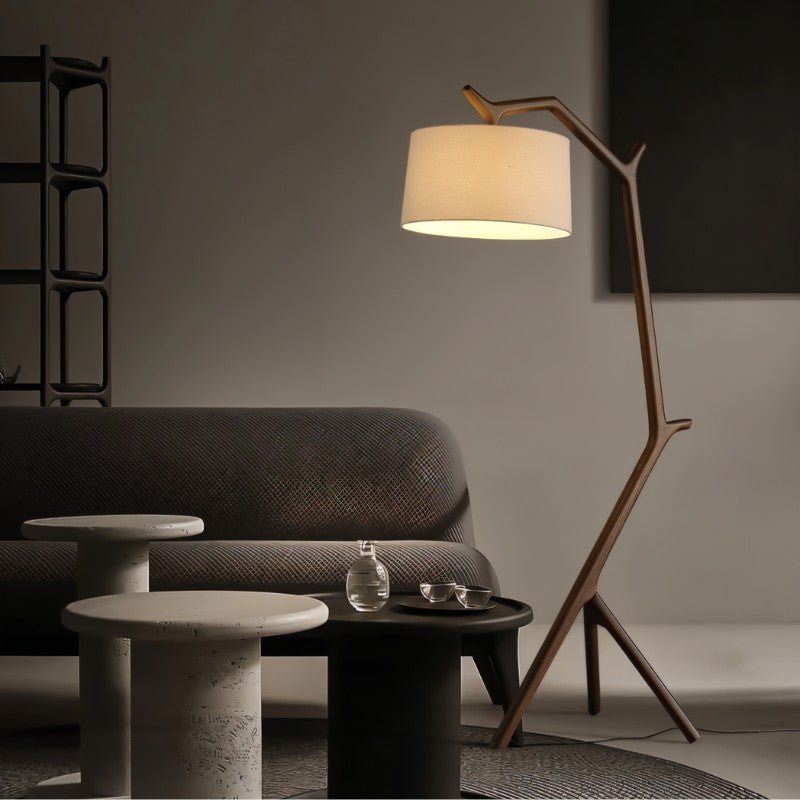 The lit lamp beside a dark sofa with two round side tables and a rug