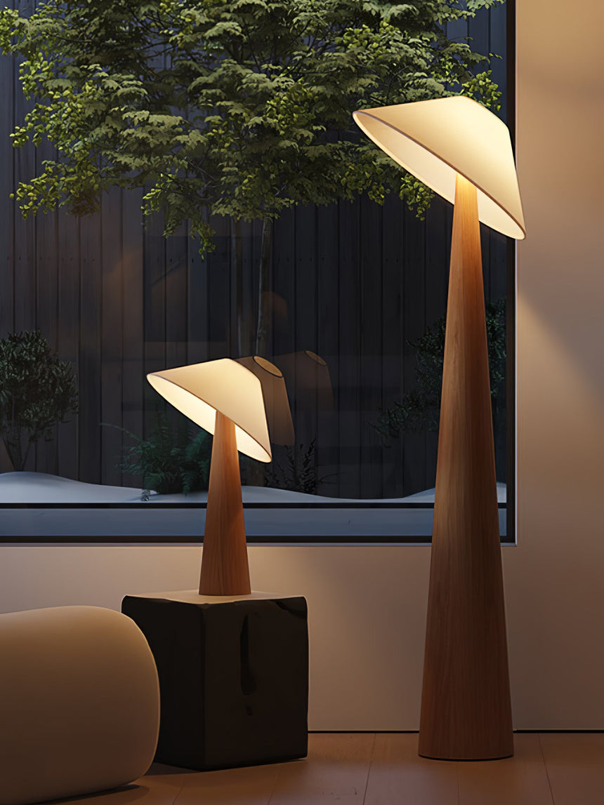 Tilted shade table lamp lit beside a window and a low wood stool