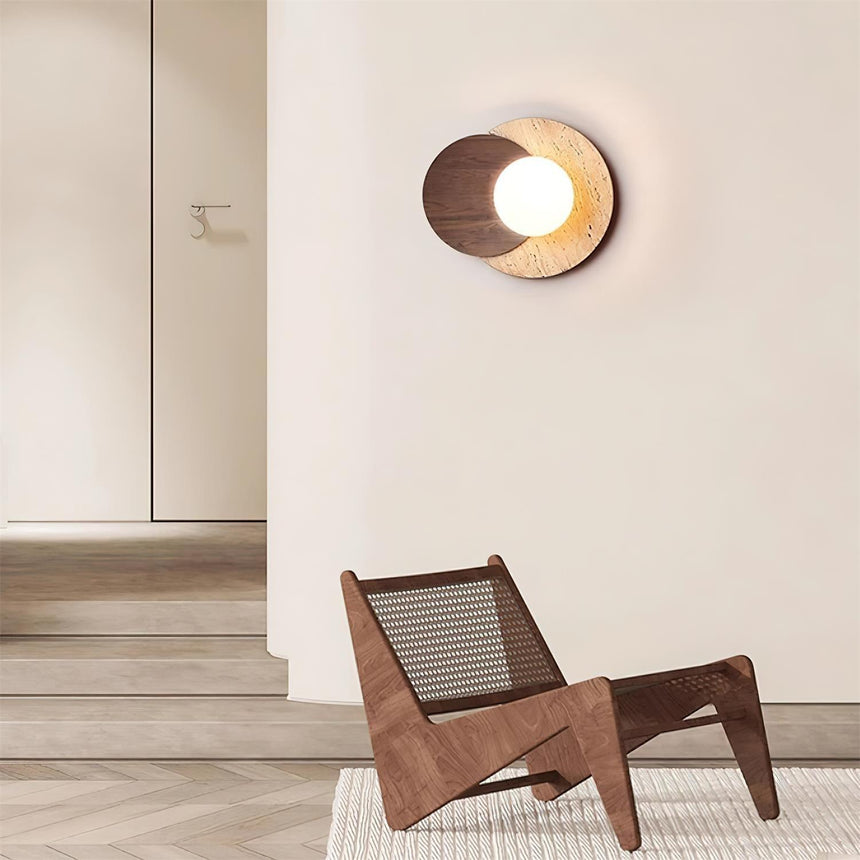 Sconce lit in a hallway above a woven wood chair on a pale floor