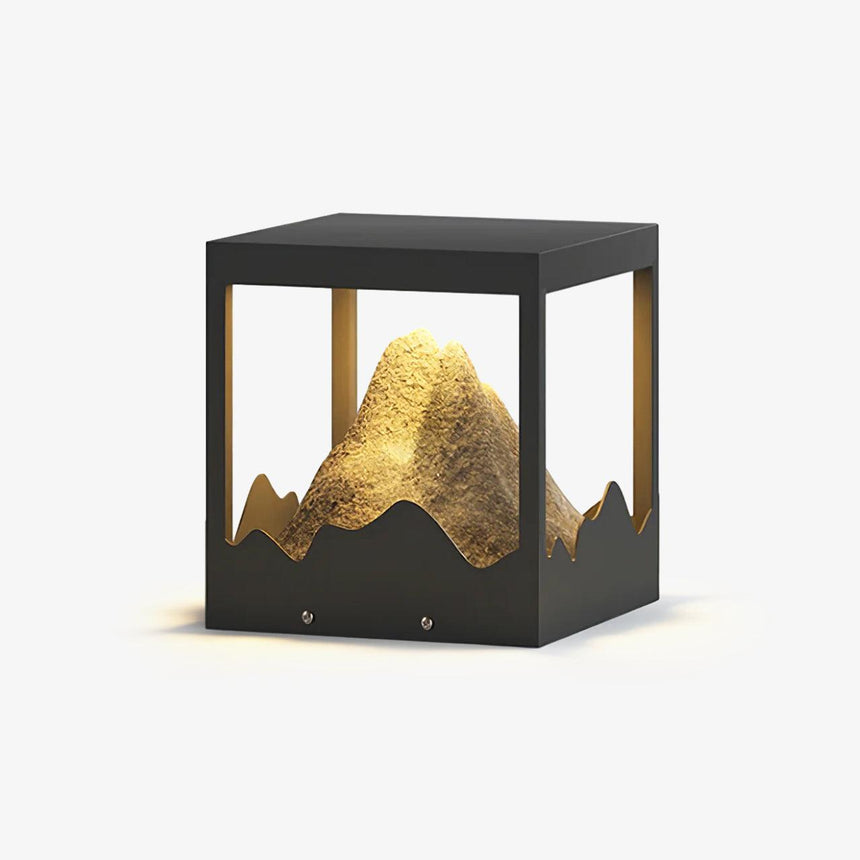 Open frame cube holding a sculpted resin mountain lit from below