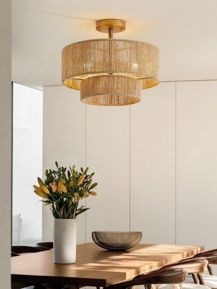 Two tier jute ceiling light above a dining table with yellow tulips in a vase