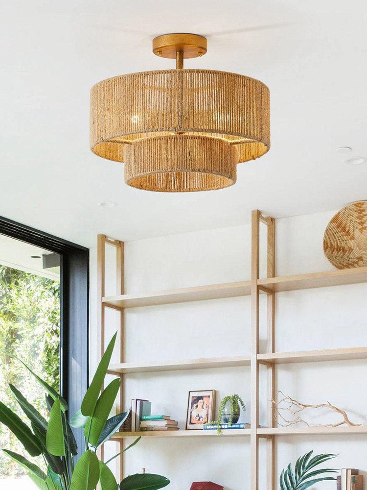 Jute ceiling light lit in a room with open shelving and a large plant