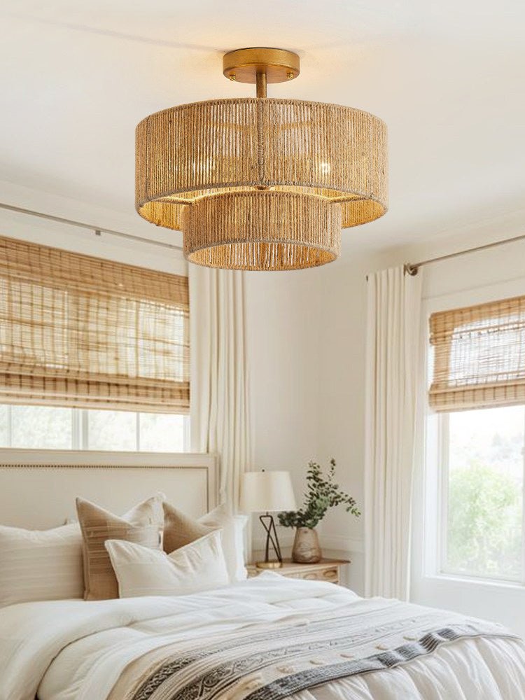 Two tier jute ceiling light above a bed with woven blinds and layered bedding