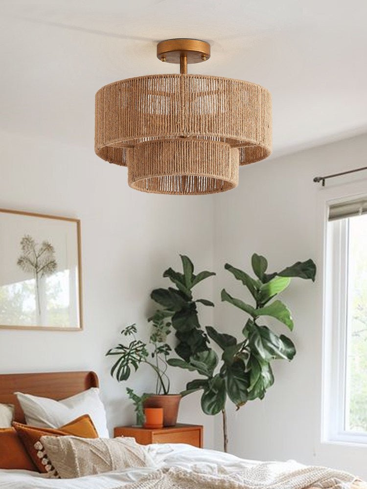 Jute ceiling light lit in a bedroom with a large plant and a leather bench