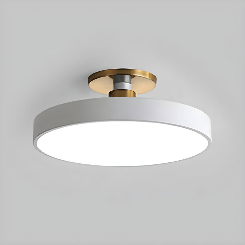 White drum ceiling light with a brass stem seen at an angle