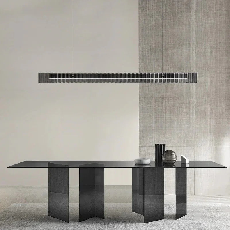 The slim lit bar hung above a long stone dining table in a bare room