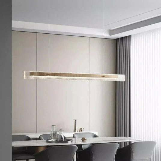 The slim lit bar hung above a kitchen island with chairs around it