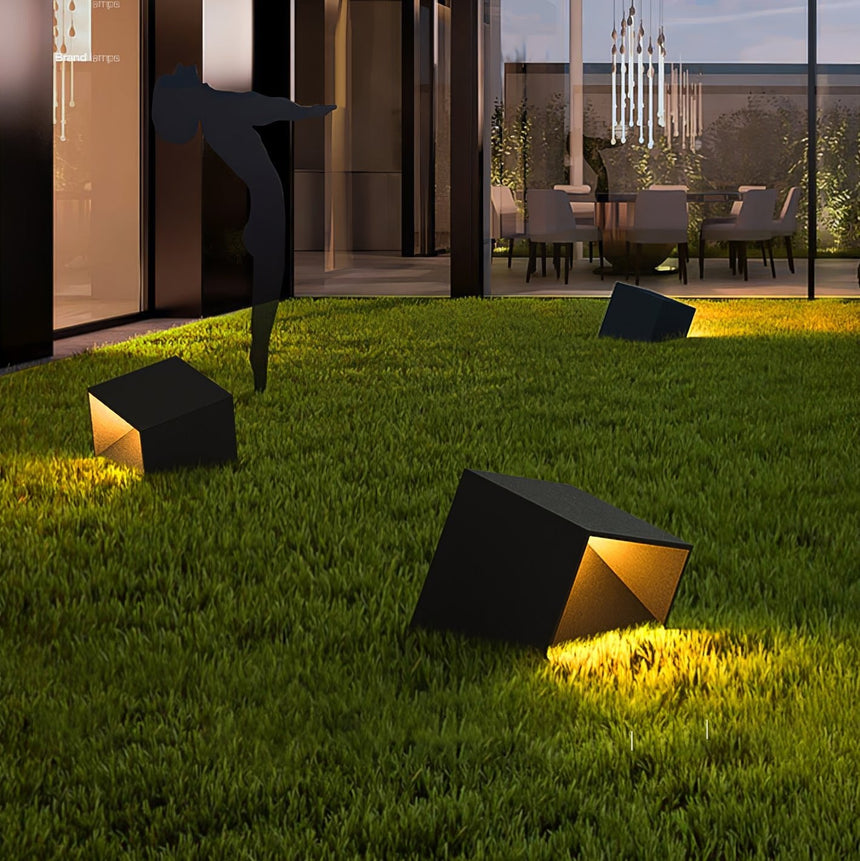 Two lit on a lawn with a lit house wall and planting behind them