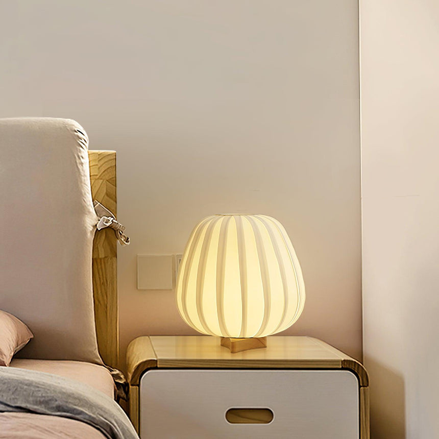 Pleated lantern lamp lit on a cabinet beside a pale armchair