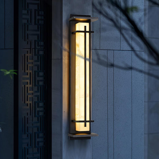 The lantern lit on a dark stone pillar beside a fretwork timber screen