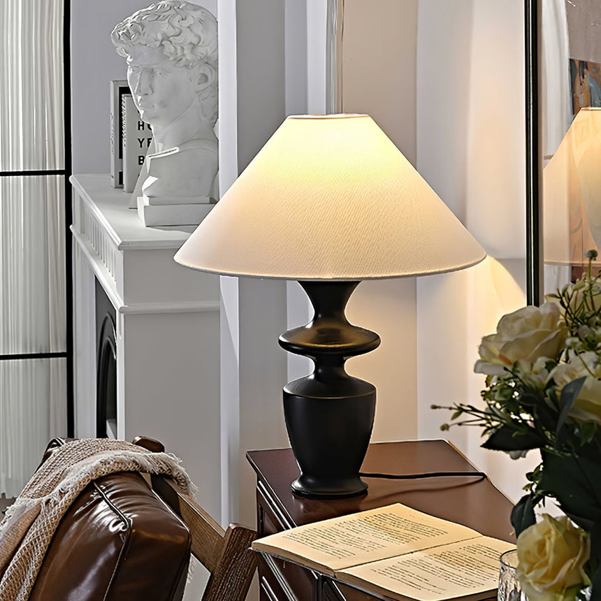 Large table lamp lit on a table beside a fireplace and an open book