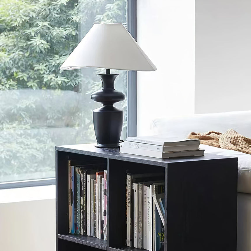 Large table lamp standing on a low bookcase in front of a bright window