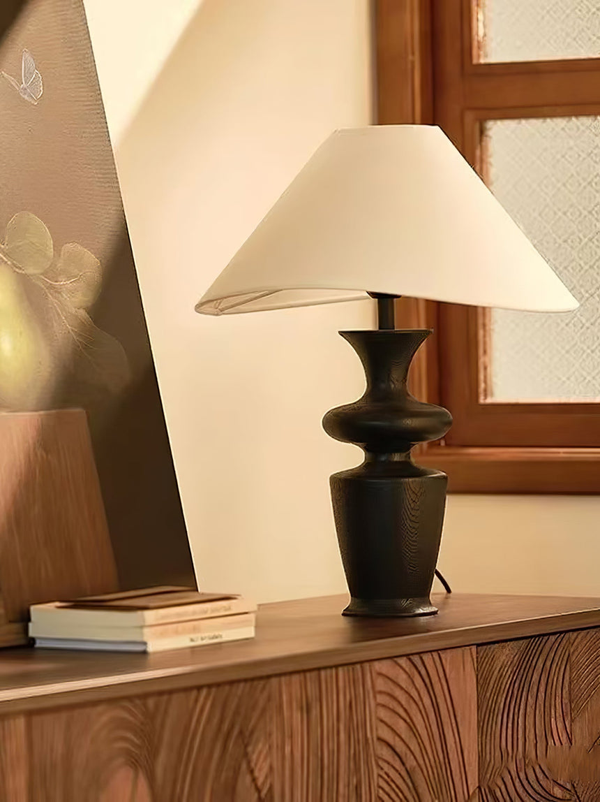 Large table lamp standing on a wooden sideboard beside a leaning panel