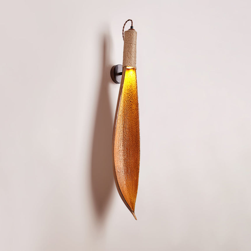 The leaf sconce seen at an angle on a plain wall, the curve of the leaf clear