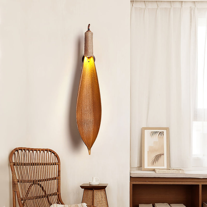 The leaf sconce above a rattan chair and a low table by a sheer curtain