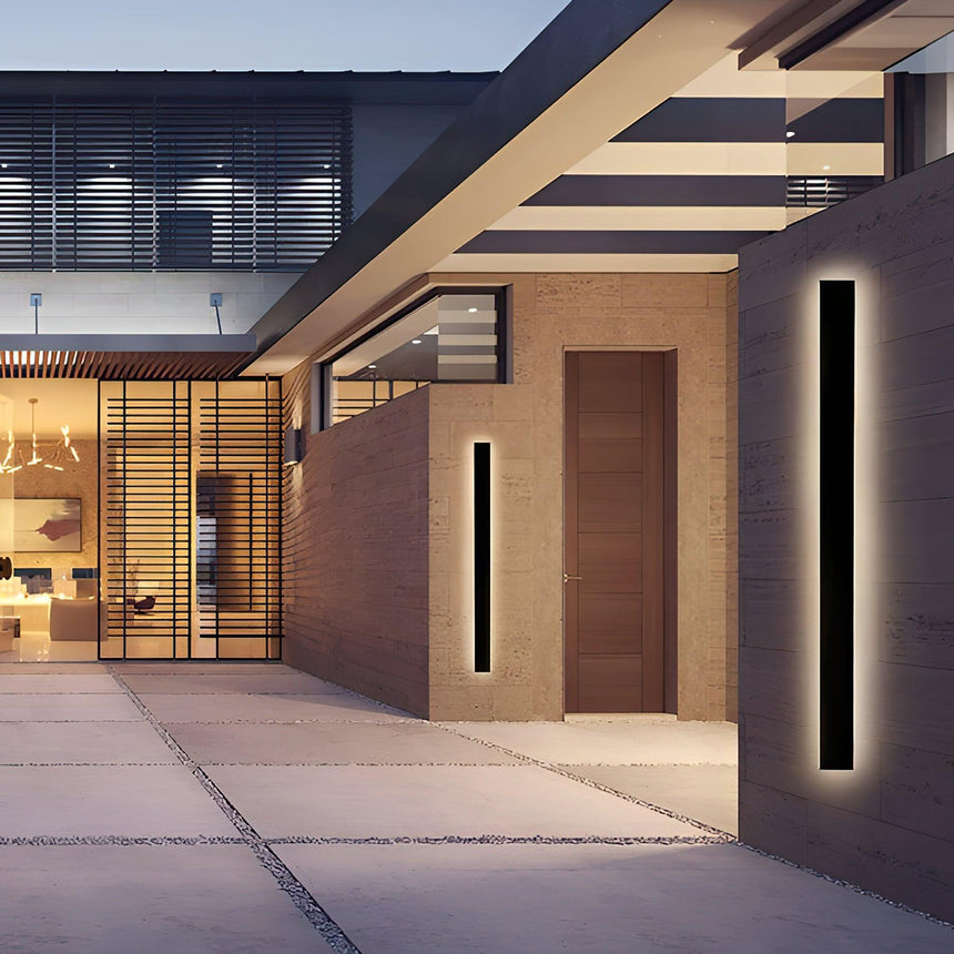 Two linear strips lit on brick walls on either side of a courtyard at dusk