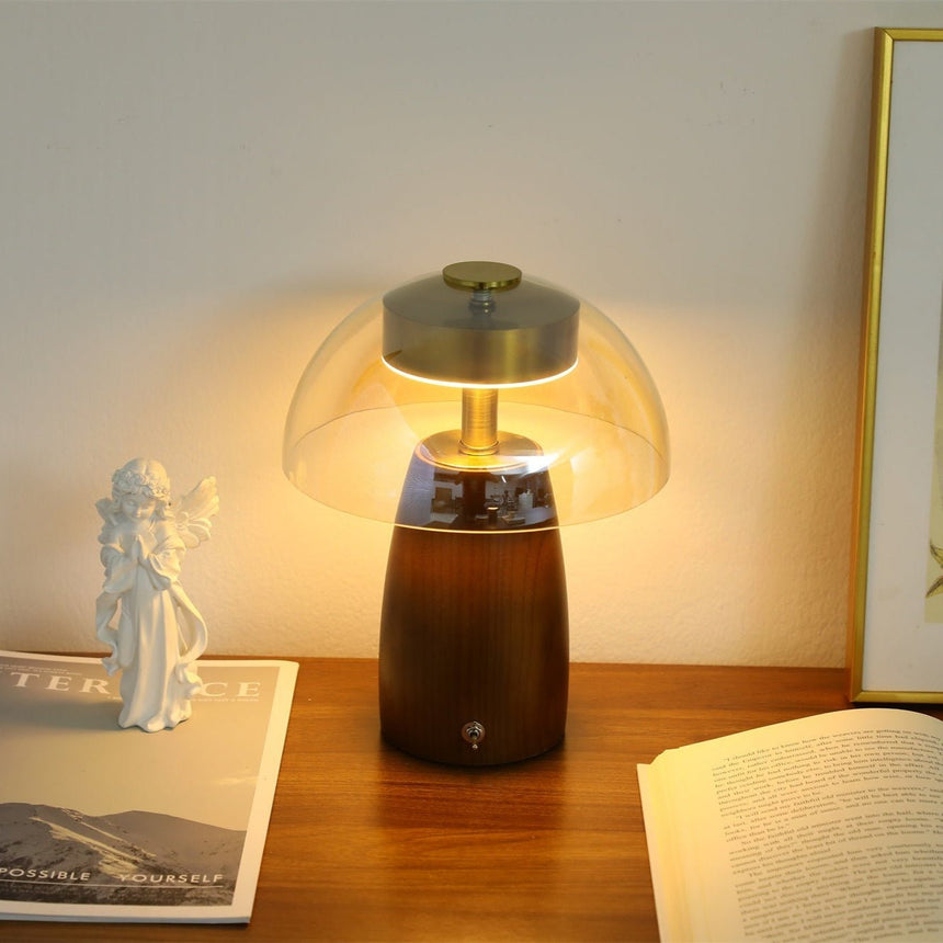 Clear dome LED table lamp lit on a desk beside an open book