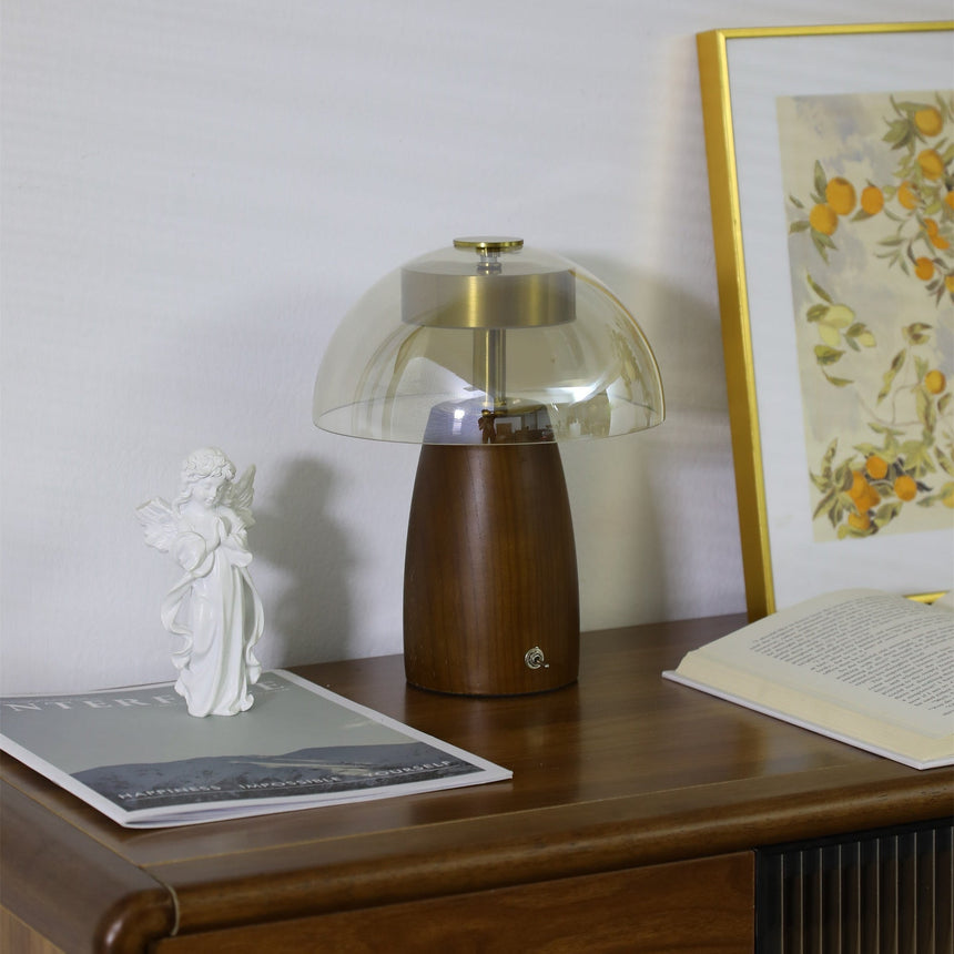 Clear dome LED table lamp lit in the corner of a wooden desk