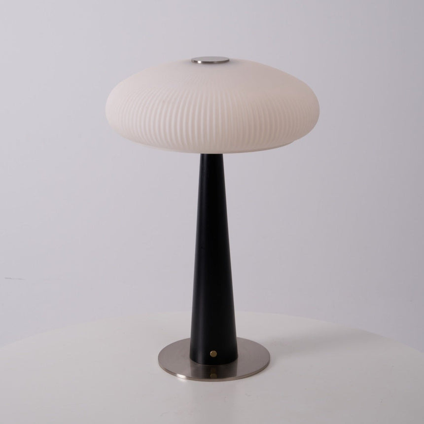 LED table lamp lit on a wooden plinth beside a lit pillar candle