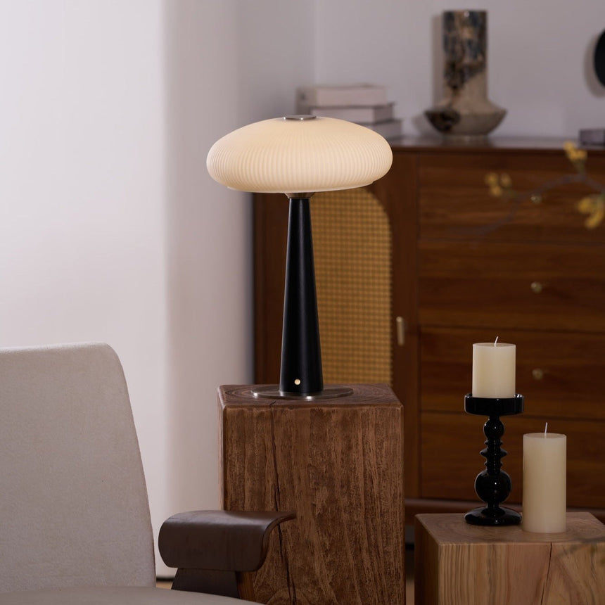 LED table lamp lit on a plinth in a warm room with candles behind