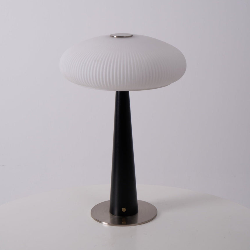 LED table lamp lit on a wooden plinth beside a cane front cabinet