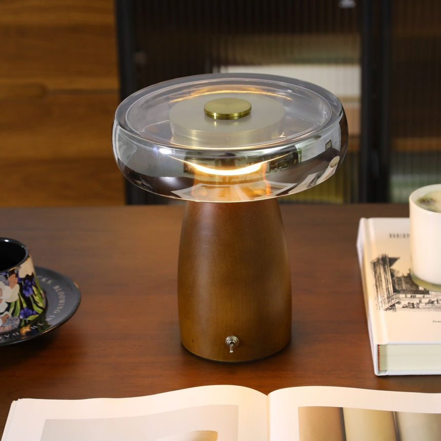 LED table lamp with the smoked glass disc lit on a wooden desk