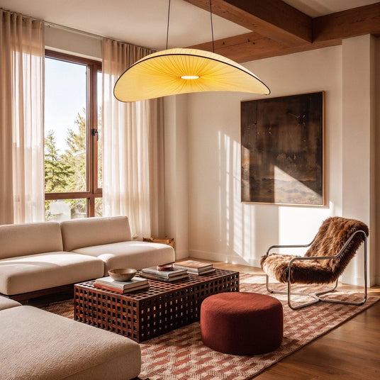 The lit shade in a living room above a long sofa, low table and a framed picture