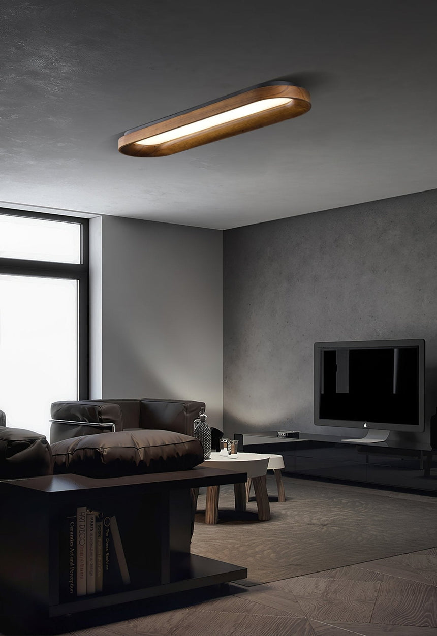 Linear ceiling light lit in a living room with a dark sofa and a screen