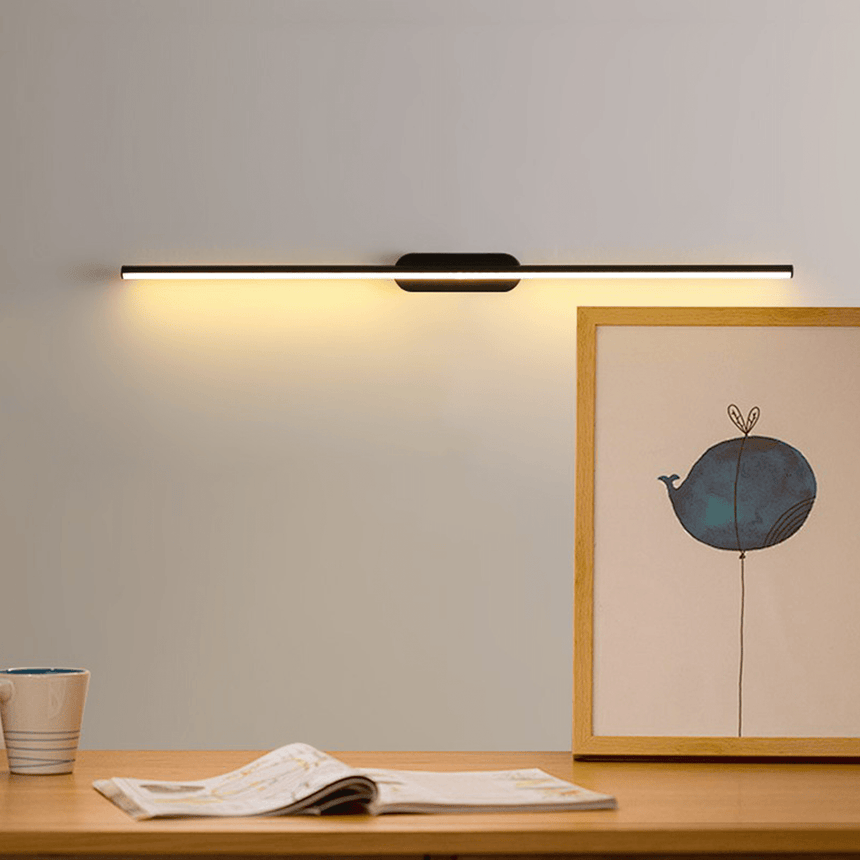 Thin rod lit above a wood surface with a framed print, a cup and a book