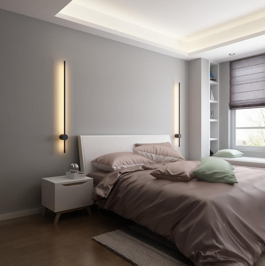 Lit beside a bed with a padded headboard, a nightstand and a window behind