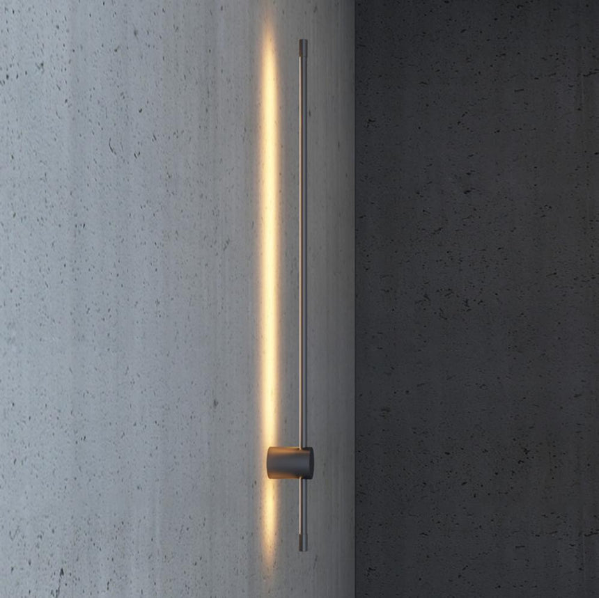 A single rod lit against a concrete wall, the light running the full length