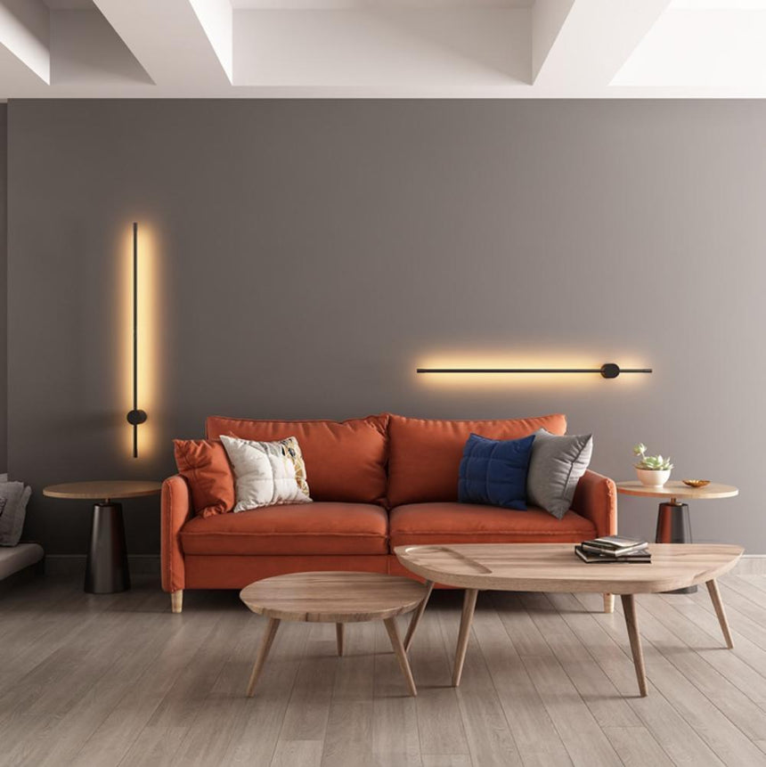 Lit above an orange sofa and a round wood coffee table with books on it