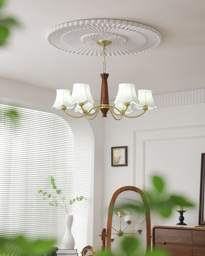 Chandelier lit beside an arched mirror above a sideboard and vase