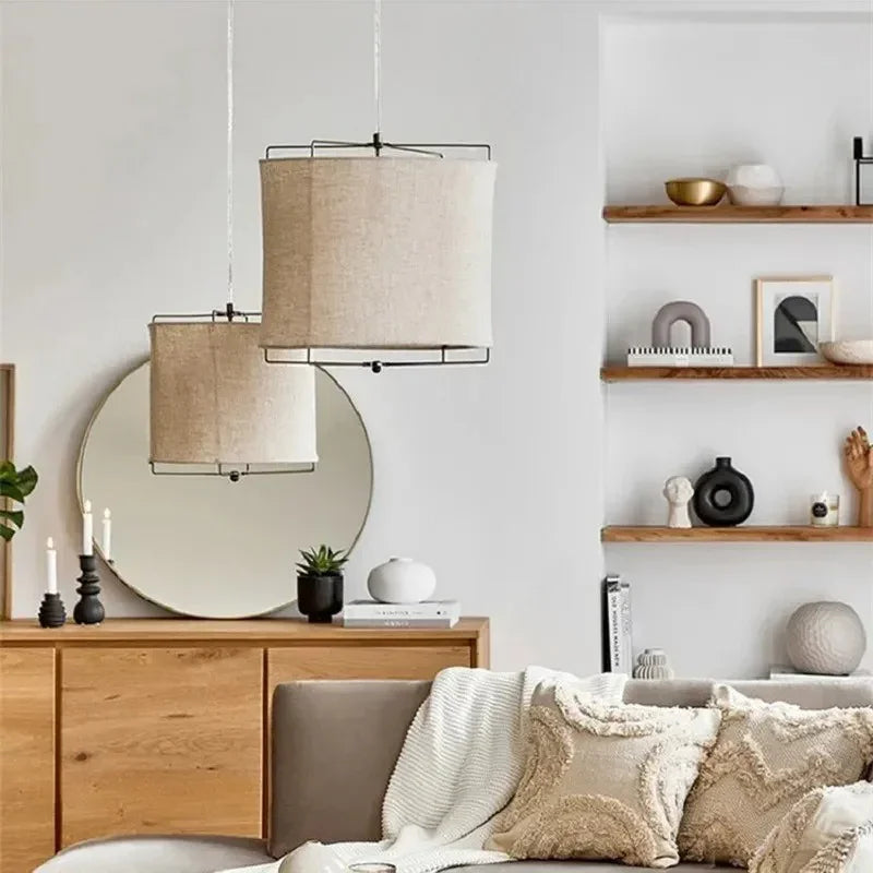 Linen drum pendant light lit in a living room beside a round mirror