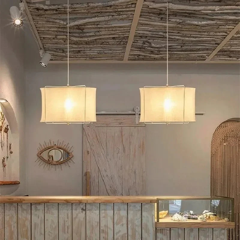 Two linen drum pendant lights hung in a row above a counter