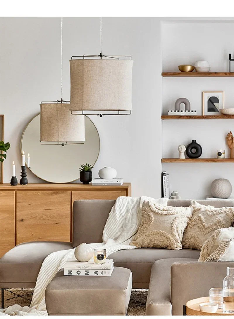 Linen drum pendant light in a living room with open shelving and a mirror