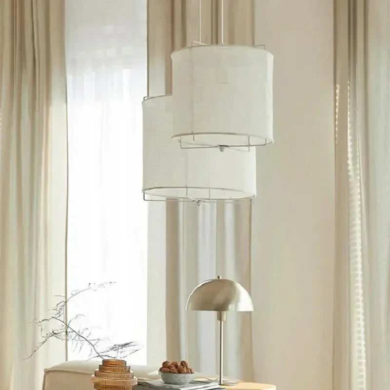 Linen drum pendant light hung in front of a tall curtained window