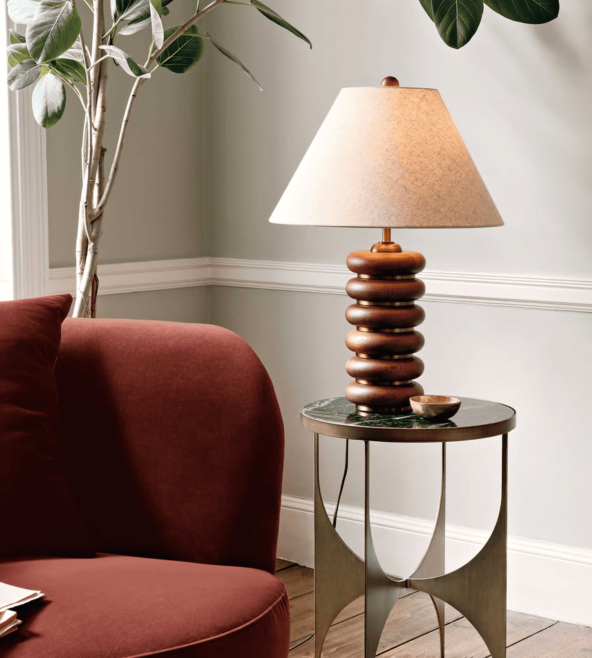 Linen shade table lamp on a side table beside a deep red chair