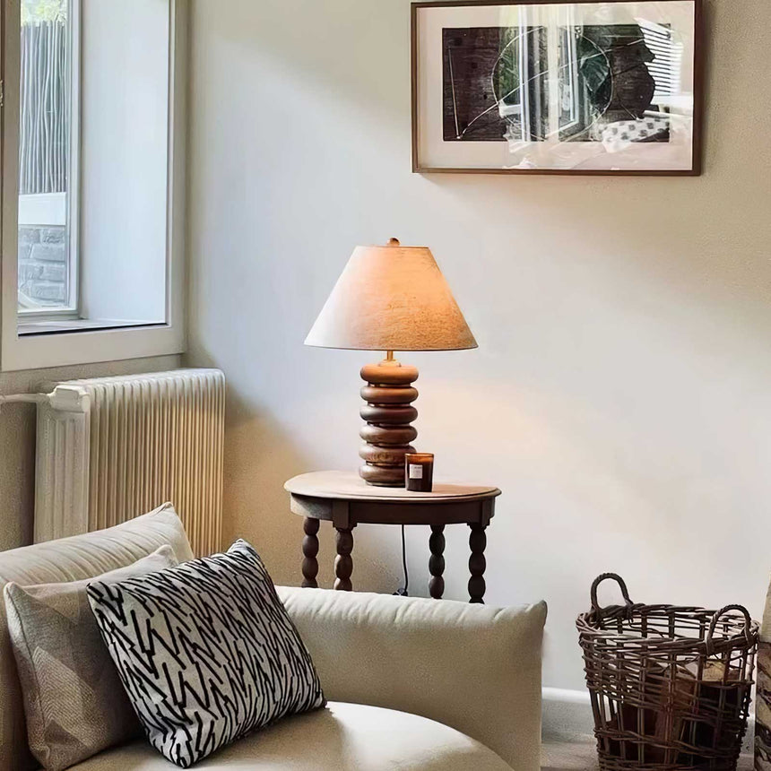 Linen shade table lamp lit on a console table beside a window
