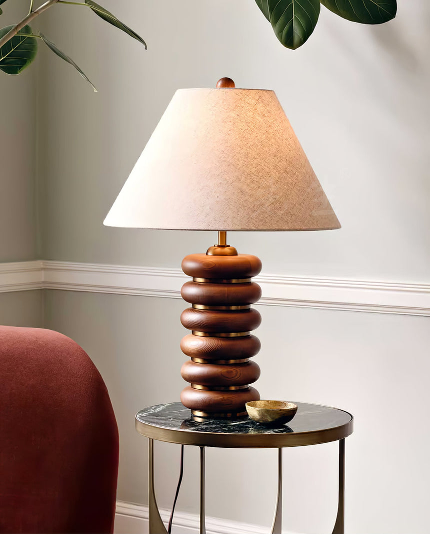 Linen shade table lamp lit on a side table beside a red armchair