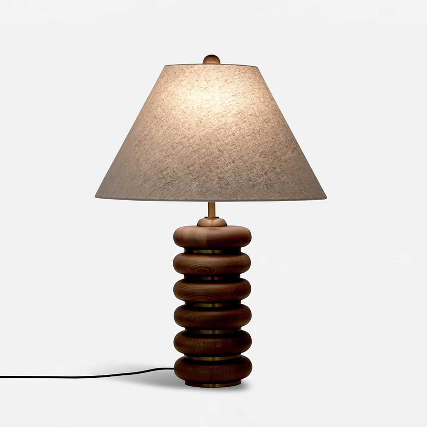Linen shade table lamp lit on a plain ground, the rings in profile
