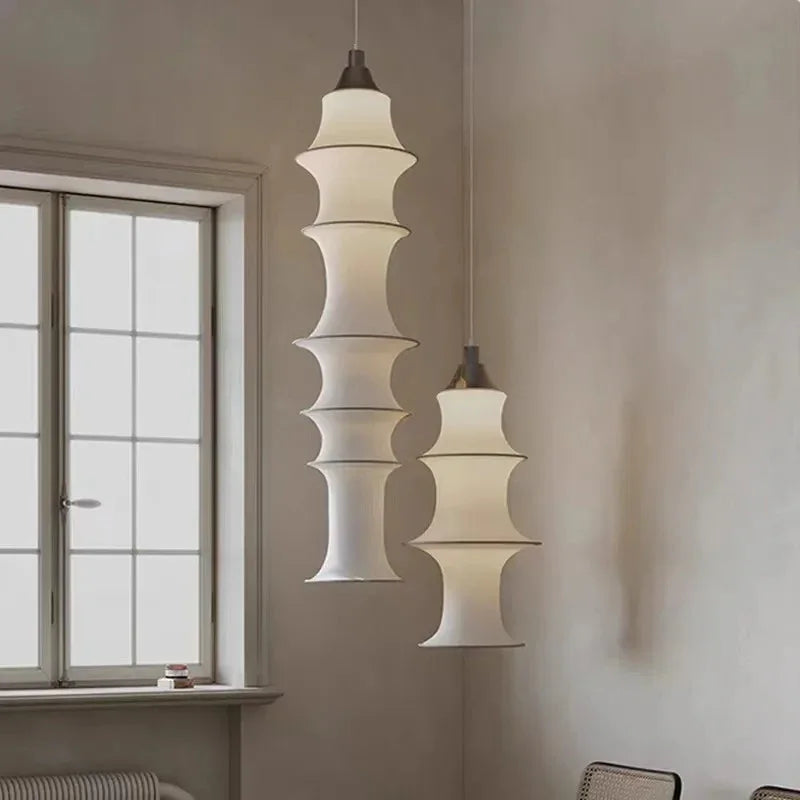 Stacked silk column lit beside a tall window in a pale room