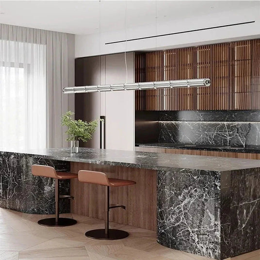 The ribbed glass bar lit above a marble kitchen island with bar stools