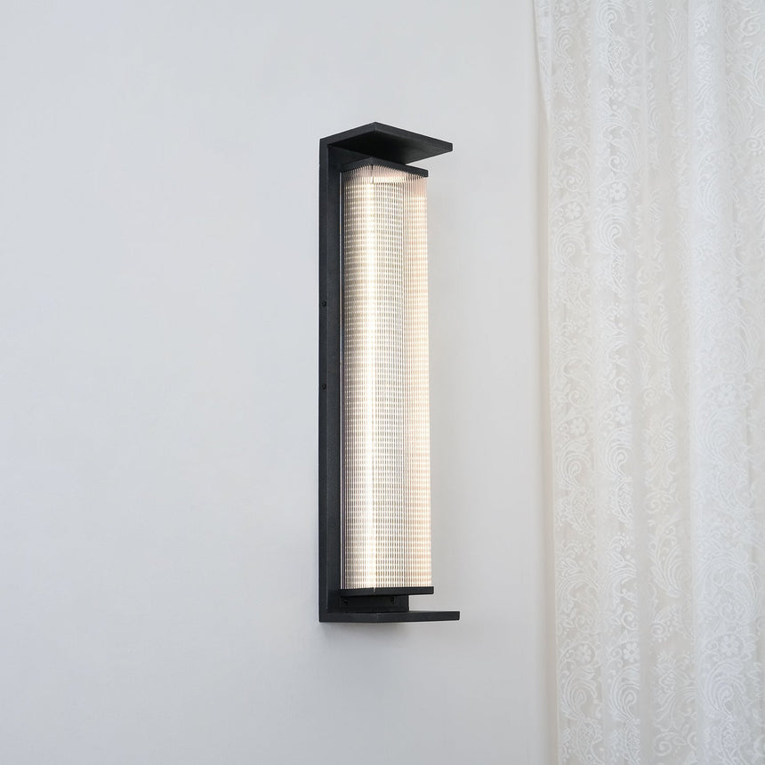 The light lit beside a green entry door with a tree reflected in glass