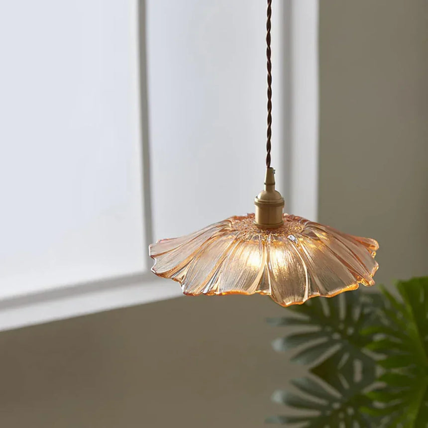 An amber shade lit beside a window with a green plant to one side